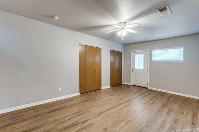 foyer featuring light wood finished floors, baseboards, visible vents, and a ceiling fan