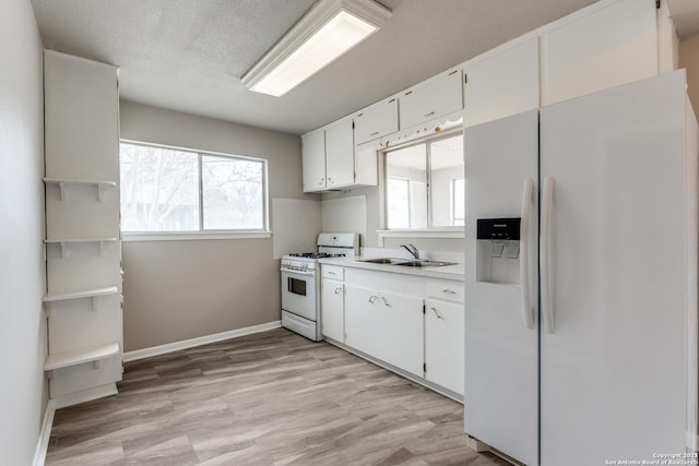 kitchen with light wood-style flooring, white appliances, a sink, white cabinets, and light countertops