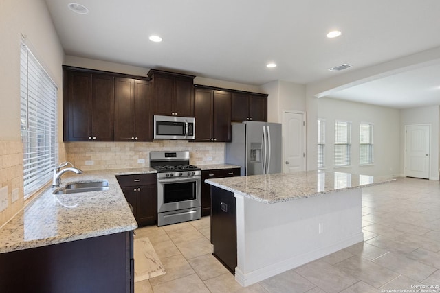 kitchen with a center island, stainless steel appliances, tasteful backsplash, visible vents, and a sink