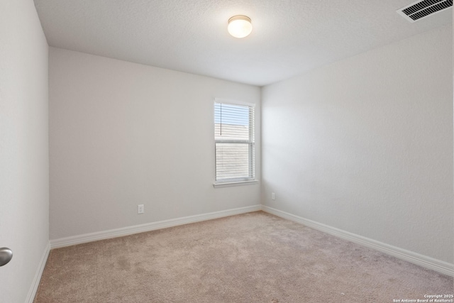 carpeted empty room with a textured ceiling, visible vents, and baseboards