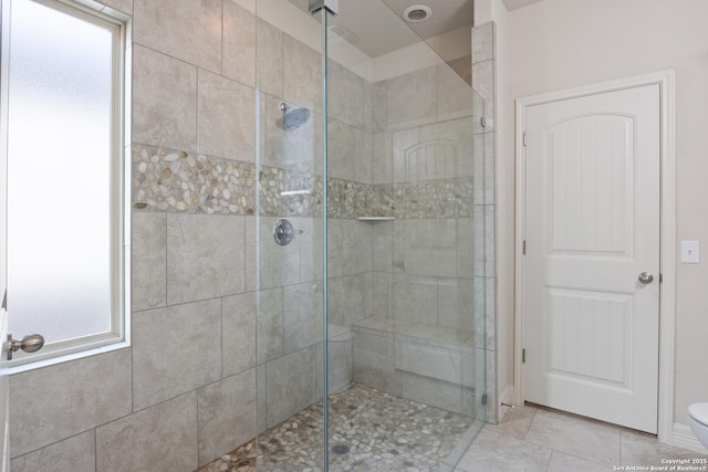 bathroom with a shower stall, toilet, and tile patterned floors