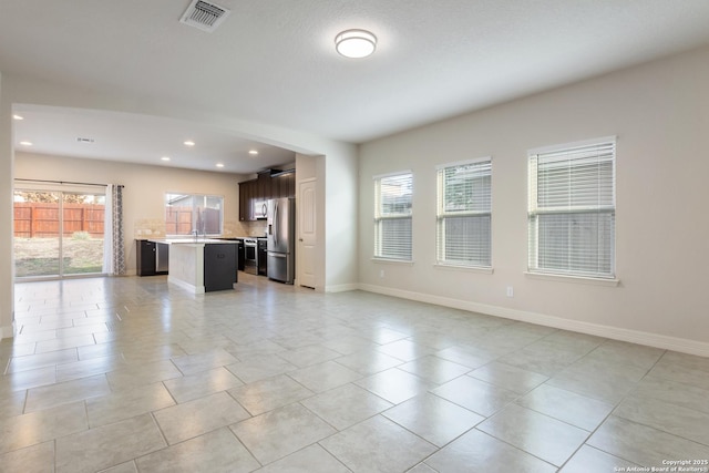 unfurnished living room featuring baseboards, visible vents, a sink, and recessed lighting