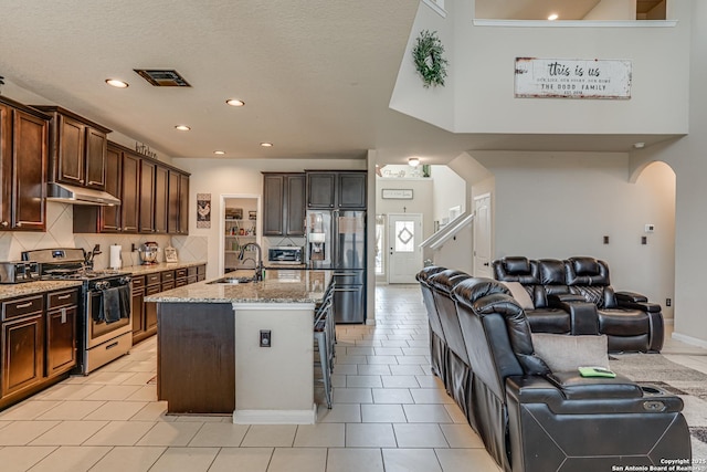 kitchen featuring stainless steel appliances, visible vents, open floor plan, a sink, and under cabinet range hood