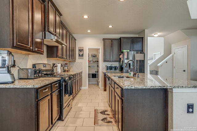 kitchen featuring stainless steel appliances, an island with sink, under cabinet range hood, and dark brown cabinets