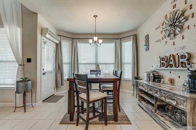 dining space with light tile patterned floors, baseboards, a wall unit AC, an inviting chandelier, and a textured ceiling