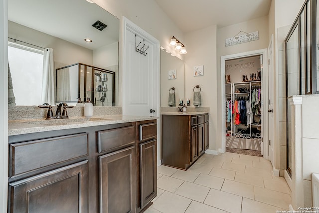 full bathroom with a shower stall, a spacious closet, tile patterned flooring, and vanity