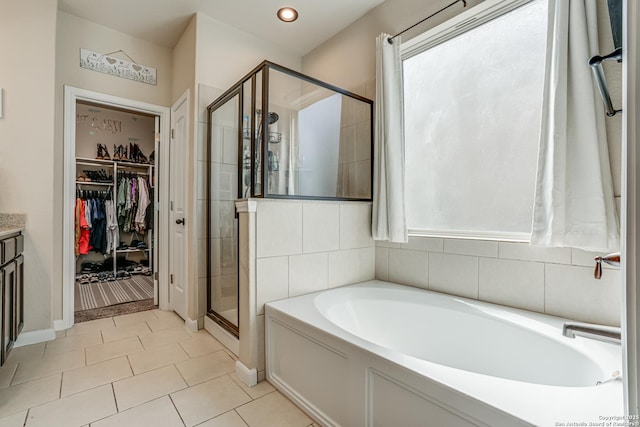 bathroom featuring a stall shower, tile patterned floors, a spacious closet, and a bath