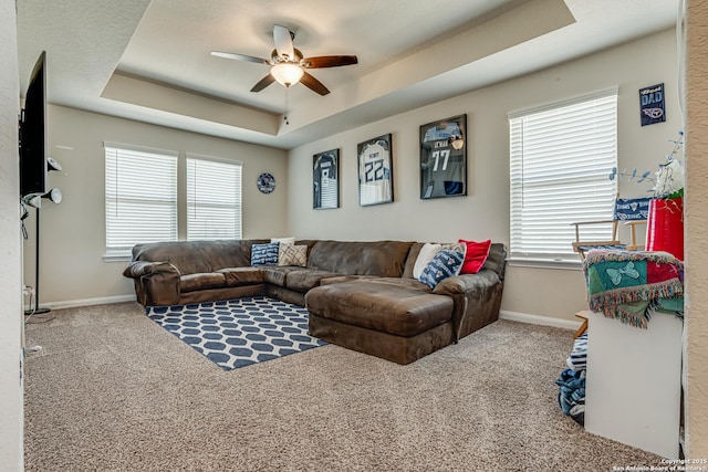 living room with carpet floors, a tray ceiling, and a healthy amount of sunlight