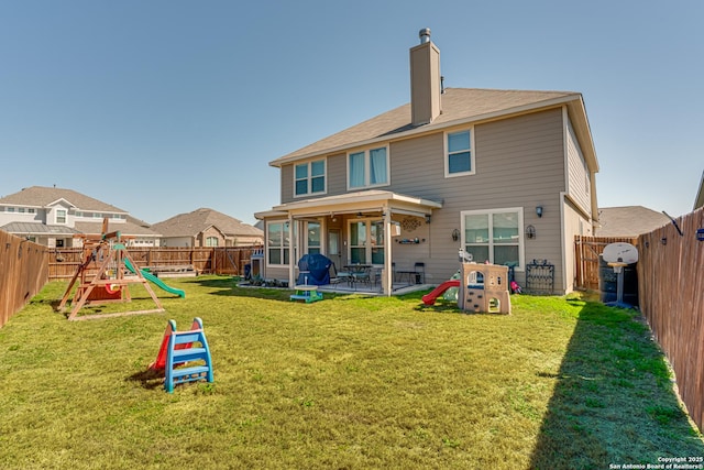 back of house with a yard, a chimney, a playground, and a fenced backyard