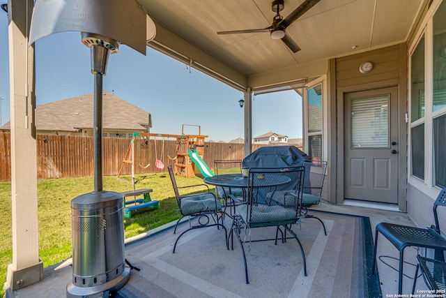 view of patio / terrace featuring outdoor dining space, a fenced backyard, ceiling fan, and a playground