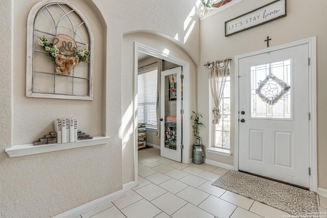 foyer with light tile patterned floors, baseboards, and a textured wall