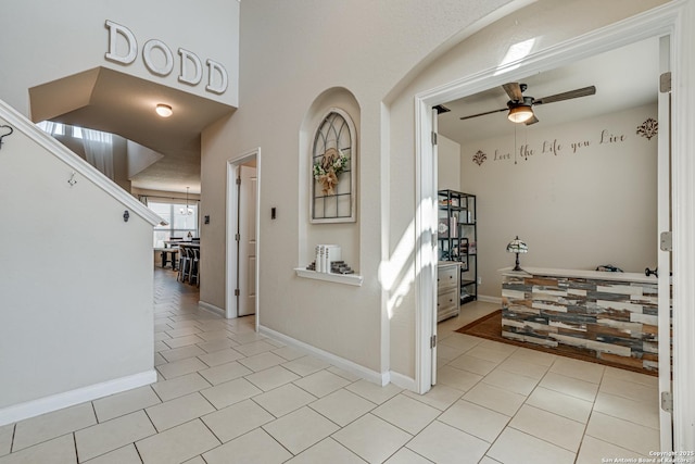 corridor featuring light tile patterned flooring and baseboards