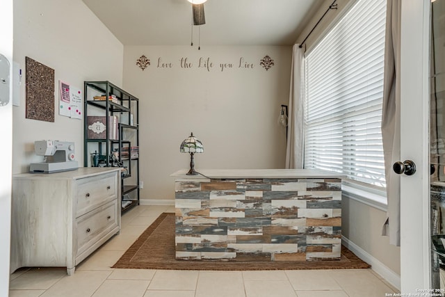 interior space with a ceiling fan, light tile patterned flooring, and baseboards