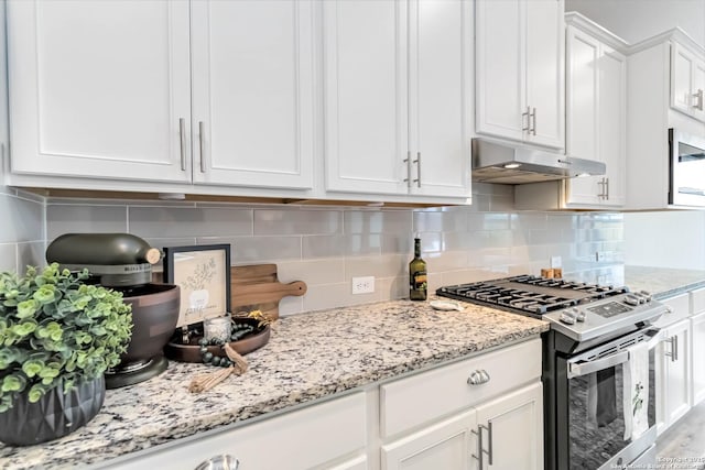 kitchen with light stone counters, under cabinet range hood, white cabinets, decorative backsplash, and stainless steel gas stove