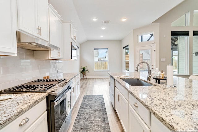 kitchen featuring visible vents, appliances with stainless steel finishes, a sink, under cabinet range hood, and backsplash