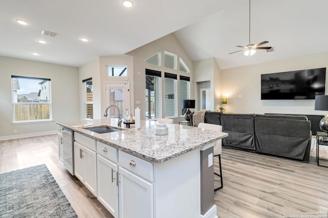 kitchen with a sink, white cabinets, open floor plan, dishwasher, and an island with sink