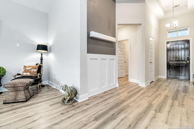 foyer entrance featuring a chandelier, wood finished floors, visible vents, and baseboards