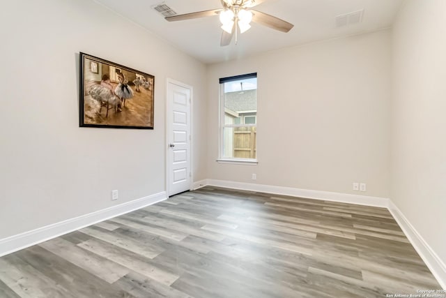 unfurnished room with a ceiling fan, wood finished floors, visible vents, and baseboards