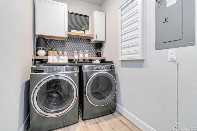 washroom featuring cabinet space, separate washer and dryer, light wood-type flooring, electric panel, and baseboards