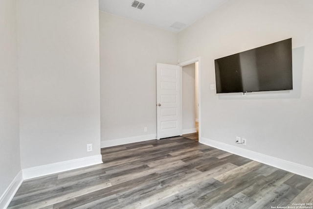 spare room with visible vents, baseboards, and wood finished floors