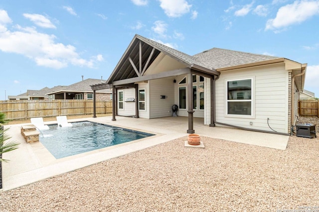 rear view of house with a fenced in pool, a fenced backyard, a patio, and roof with shingles