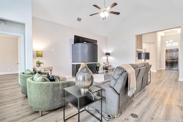 living area featuring light wood-style flooring, high vaulted ceiling, baseboards, and ceiling fan with notable chandelier