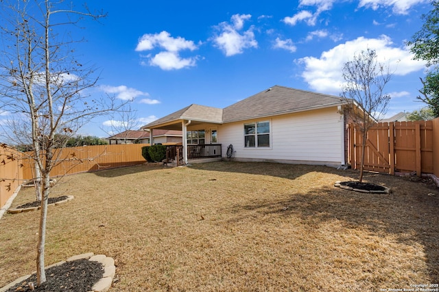 rear view of property featuring a fenced backyard and a lawn