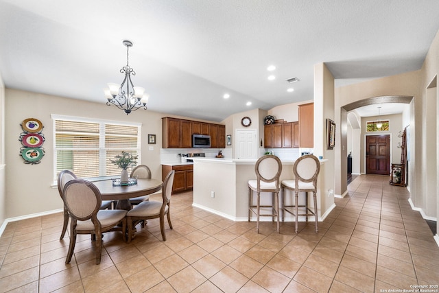 dining space featuring light tile patterned floors, arched walkways, visible vents, vaulted ceiling, and a notable chandelier