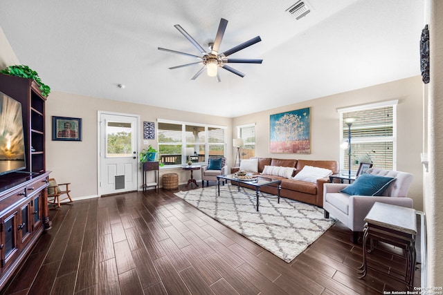 living area with dark wood-type flooring, visible vents, ceiling fan, and baseboards