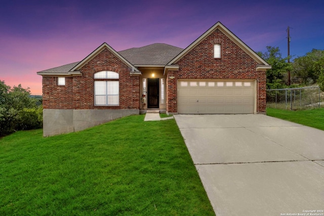 single story home featuring brick siding, a yard, driveway, and an attached garage