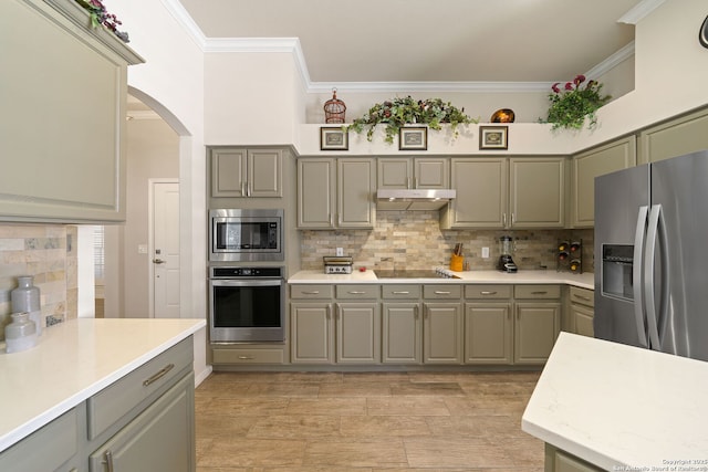 kitchen with stainless steel appliances, gray cabinets, ornamental molding, and under cabinet range hood