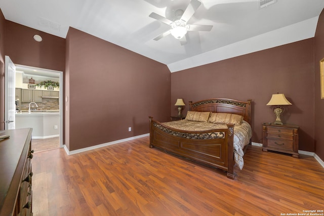 bedroom featuring lofted ceiling, ceiling fan, wood finished floors, visible vents, and baseboards