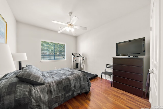 bedroom with ceiling fan, wood finished floors, visible vents, and baseboards