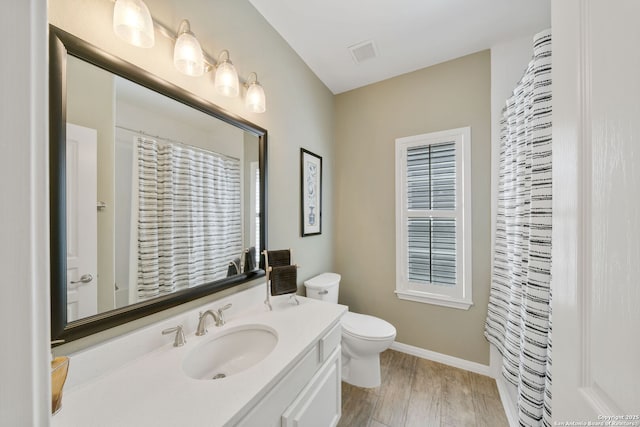 bathroom with toilet, wood finished floors, vanity, visible vents, and baseboards