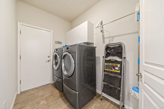 washroom with light wood-style floors, cabinet space, washer and clothes dryer, and heating unit