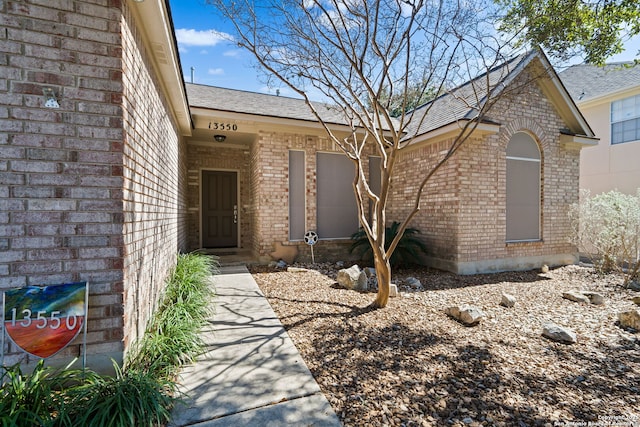 property entrance with roof with shingles and brick siding