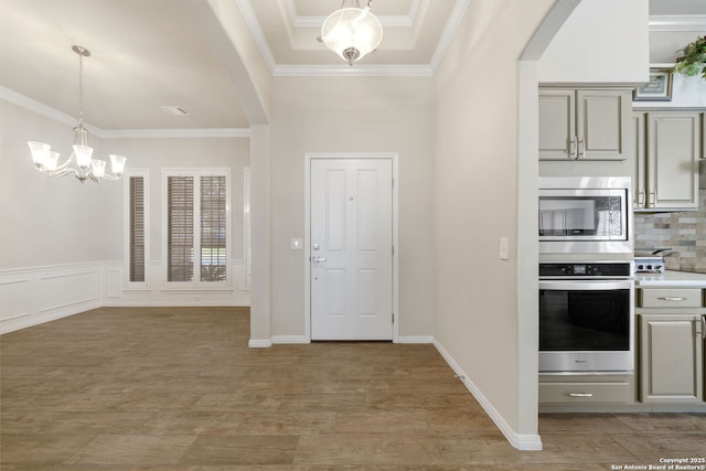 kitchen featuring appliances with stainless steel finishes, arched walkways, gray cabinets, and ornamental molding