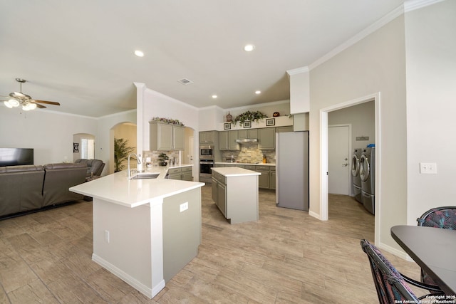 kitchen featuring arched walkways, gray cabinets, appliances with stainless steel finishes, a sink, and separate washer and dryer