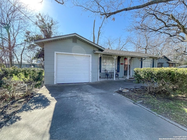 ranch-style home with a porch, concrete driveway, a shingled roof, and an attached garage