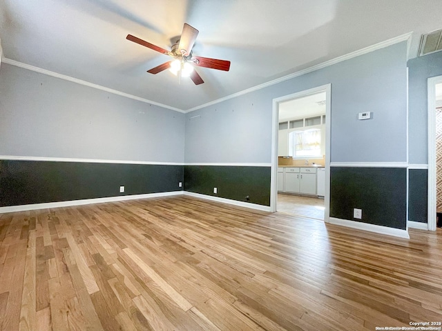 empty room with light wood finished floors, a ceiling fan, visible vents, and crown molding