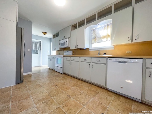 kitchen with white appliances, baseboards, light countertops, white cabinetry, and a sink