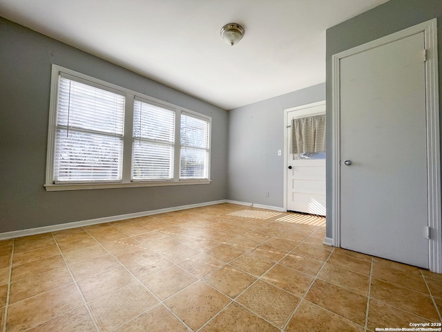 empty room featuring baseboards and light tile patterned flooring