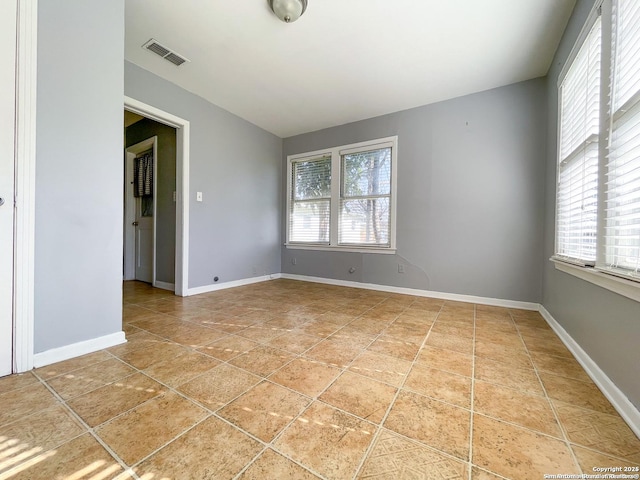 spare room featuring light tile patterned floors, plenty of natural light, visible vents, and baseboards