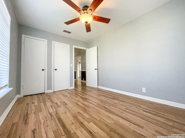 unfurnished bedroom with light wood-type flooring, baseboards, visible vents, and a ceiling fan