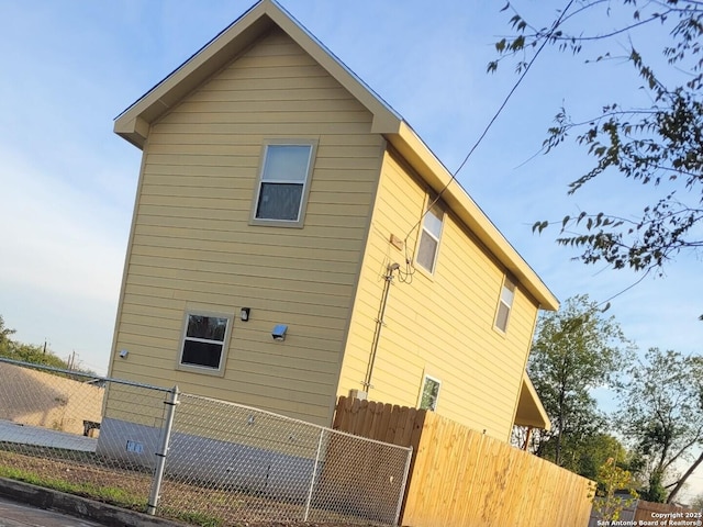 view of side of home with crawl space and fence