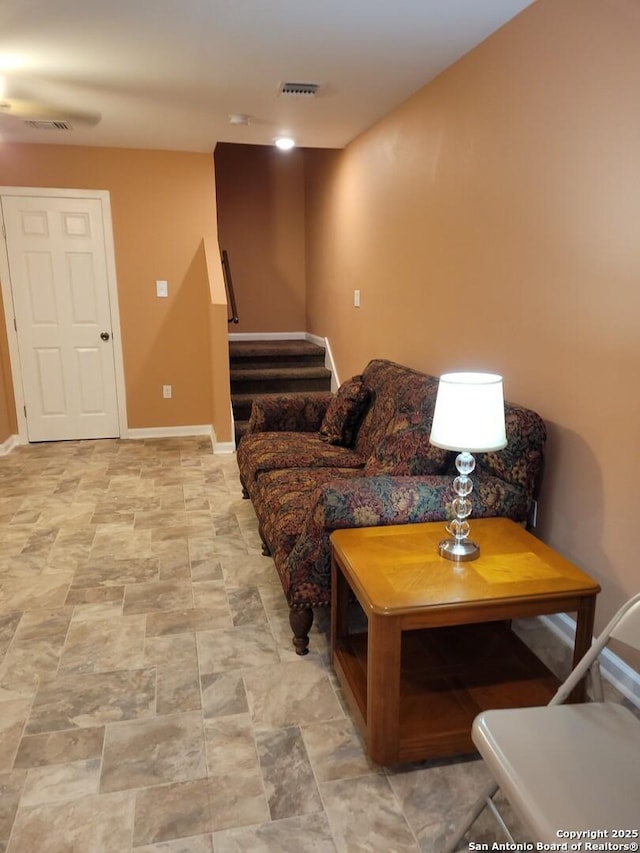 living room featuring baseboards, stairs, and visible vents