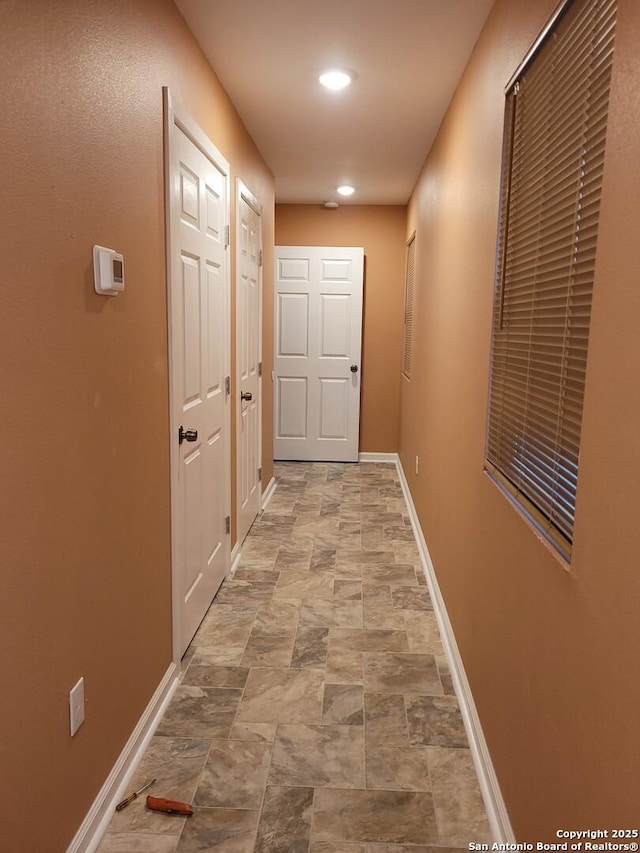 hallway with stone finish floor and baseboards