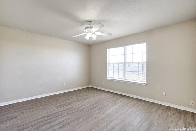 spare room with ceiling fan, a textured ceiling, wood finished floors, and baseboards