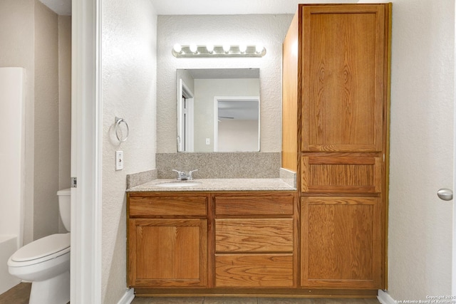 bathroom featuring a textured wall, vanity, and toilet