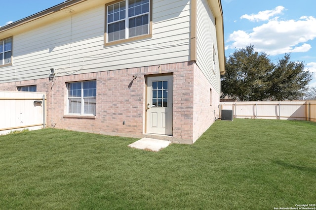 back of house with central AC, brick siding, a yard, and a fenced backyard